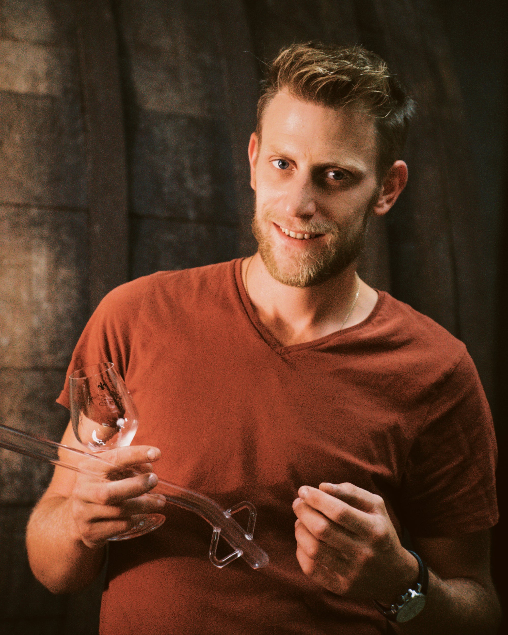 Jungwinzer Clément Fend hält ein Weinglas