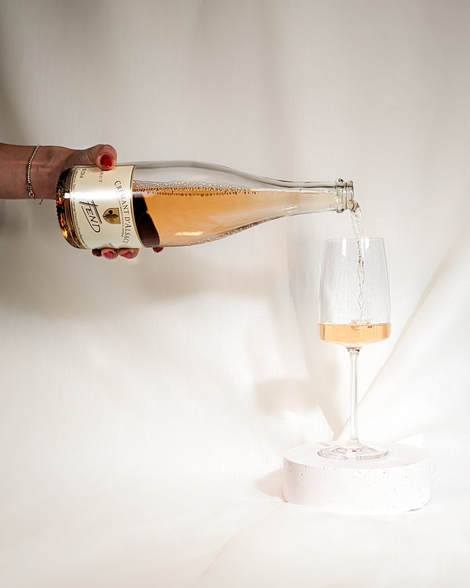 Der Cremant d'Alsace Rosé der Domaine Fend wird von links in ein Schaumweinglas eingegossen.
