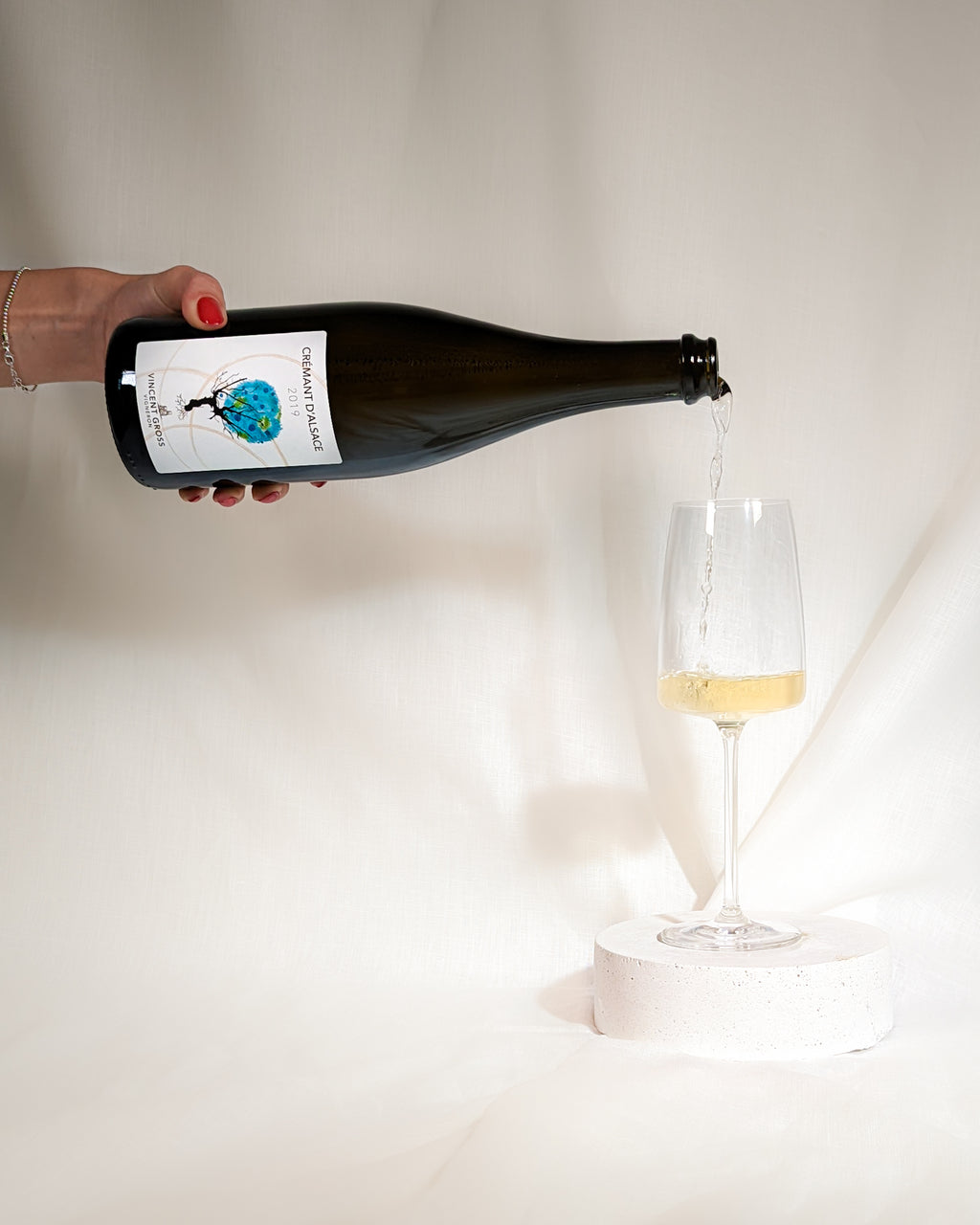 Der Cremant d'Alsace Brut Nature der Domaine Gross wird von links in ein Schaumweinglas eingegossen.