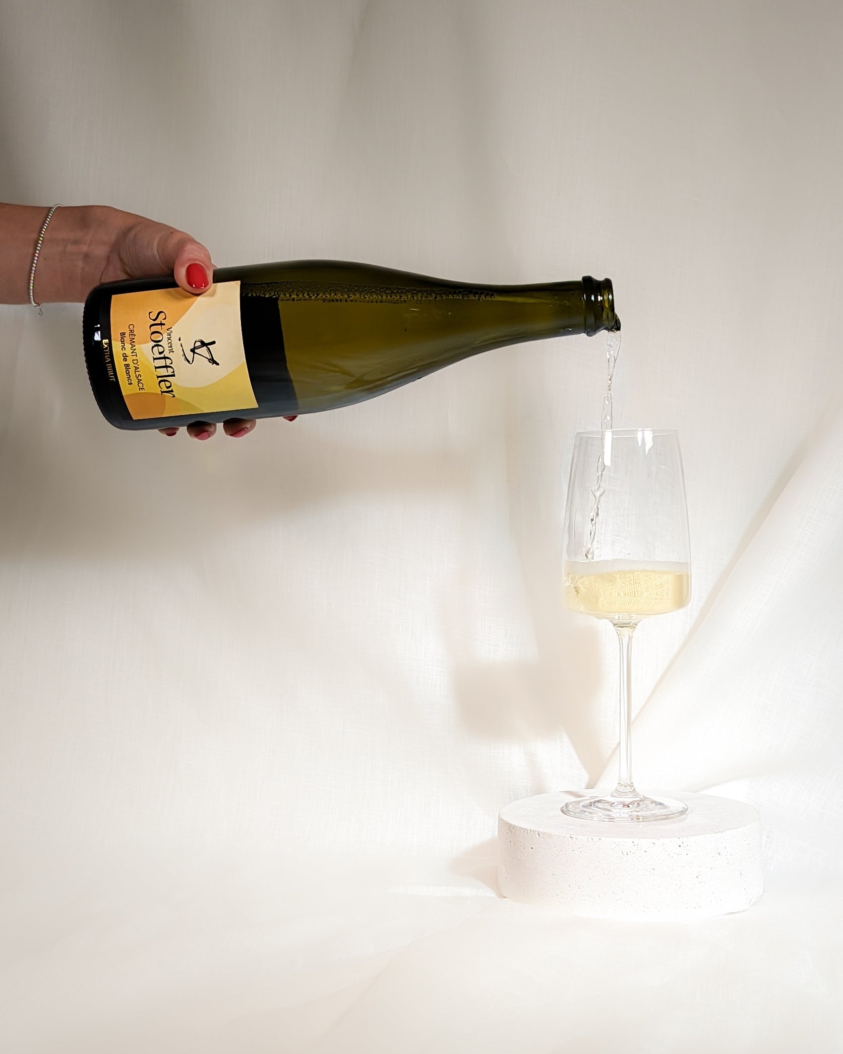 Der Cremant d'Alsace Blanc de Blanc Extra Brut der Domaine Stoeffler wird von links in ein Schaumweinglas eingegossen.