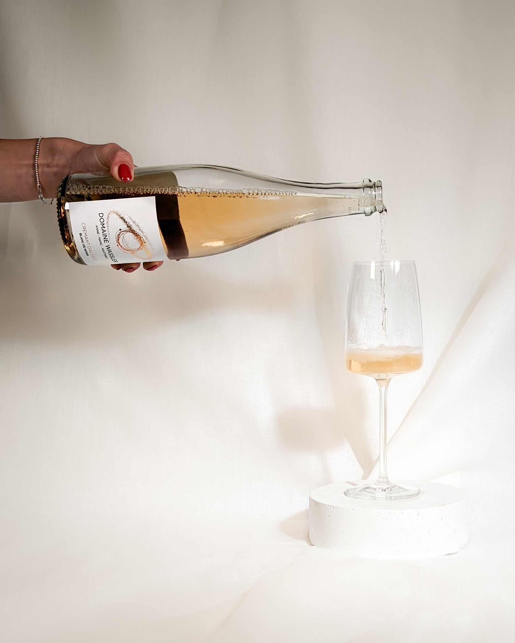 Der Cremant d'Alsace Blanc de Noir der Domaine Wassler wird von links in ein Schaumweinglas eingegossen.