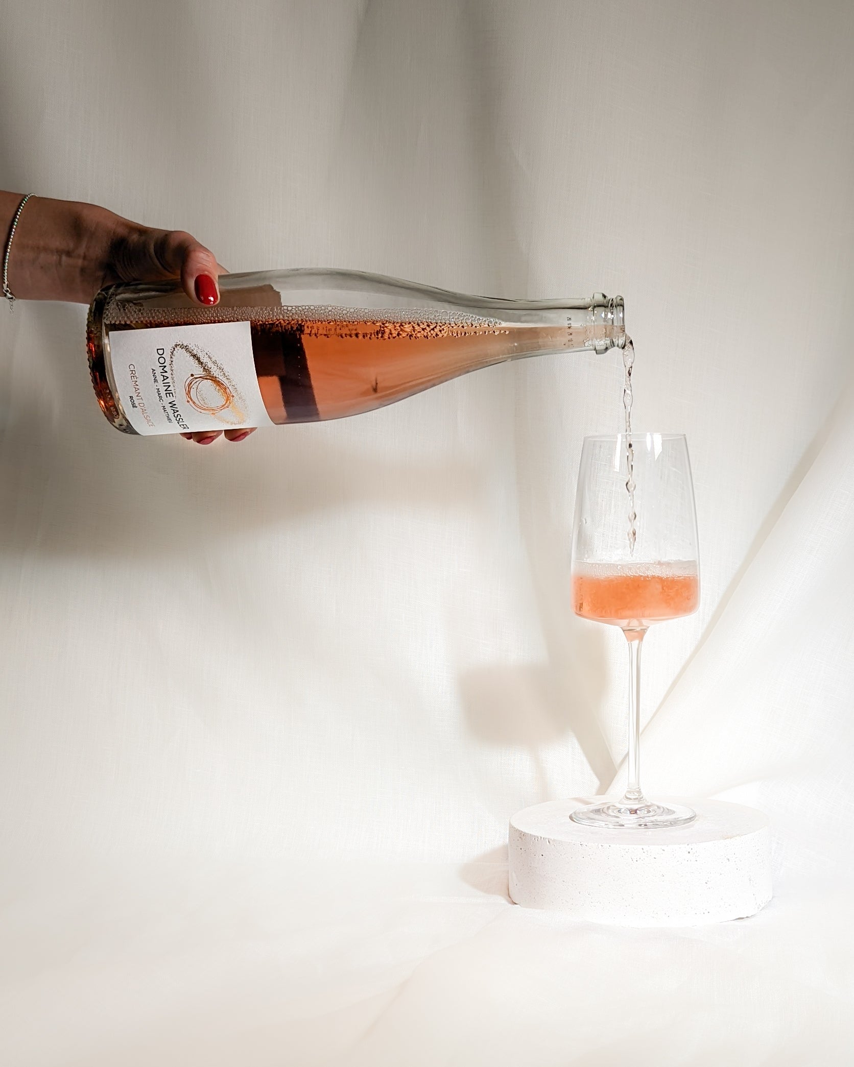 Der Cremant d'Alsace Rosé der Domaine Wassler wird von links in ein Schaumweinglas eingegossen.